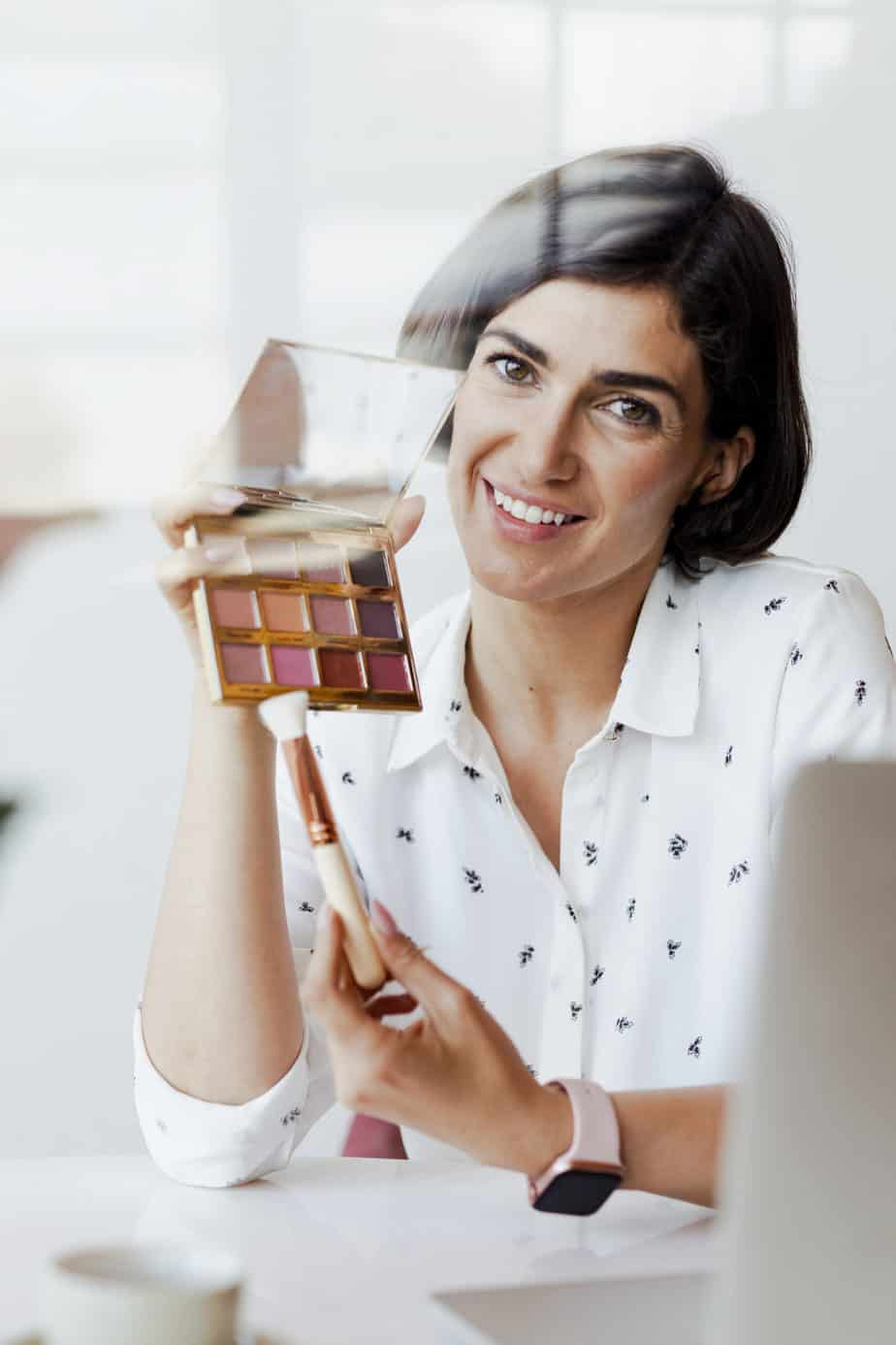 Happy women displaying an eye shadow palette with a laptop → Social Kings Grow your following