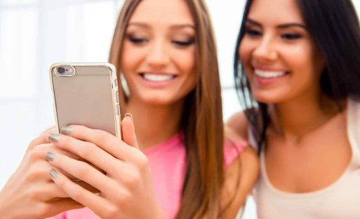 Portrait of two gossip friends reading sms on smartphone
